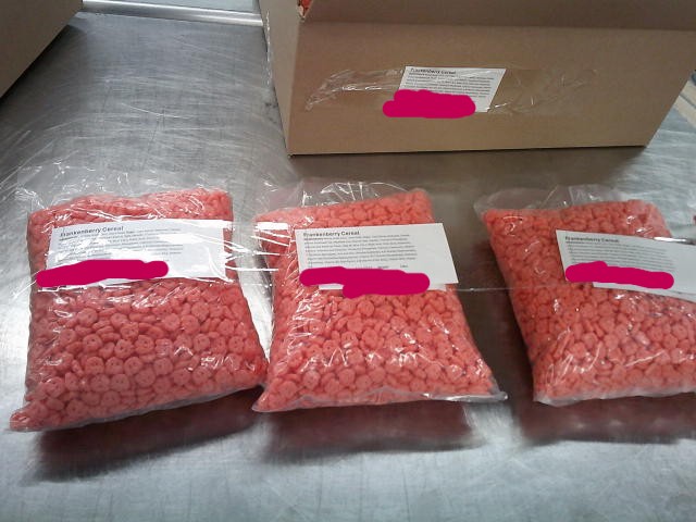 Three bags of Franken berry cereal taped with label in front of box.